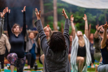 Diverse People Enjoy Spiritual Gathering A Large Group Of Multigenerational People Are Seen In A Peaceful Yoga Pose With Arms Raised In Air During A Woodland Retreat For Body And Mind.