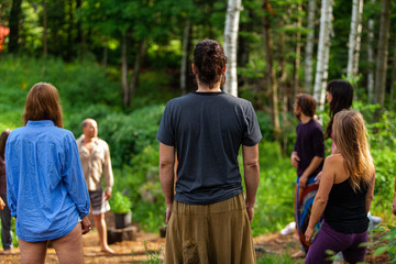 Wall Mural - Diverse people enjoy spiritual gathering A multigenerational group of individuals are seen standing in a circle in a forest clearing as they practice shamanic and native traditions in nature.