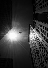 Low angle black and white photo of airplane flying in Manhattan