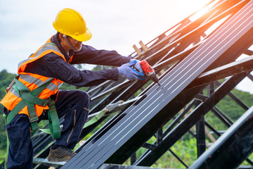 Wall Mural - Roofer worker in protective uniform wear and gloves, using air or pneumatic nail gun and installing asphalt shingle on top of the new roof,Concept of residential building under construction.