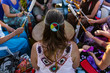Sacred drums during spiritual singing. A high angle view of a woman wearing native headband and colorful clothes during a singing circle of people around a sacred mother drum outdoors.
