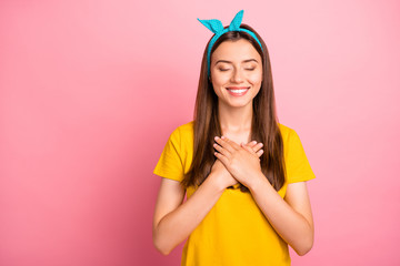 Sticker - Portrait of cute hipster closing her eyes touching chest wearing yellow t-shirt isolated over pink background