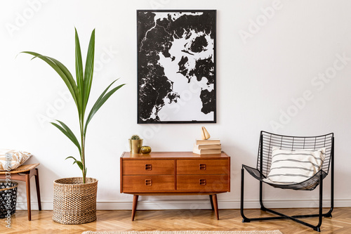 Fotomural Stylish interior design of living room with wooden retro commode, chair, tropical plant in rattan pot, basket and elegant personal accessories