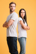 © LIGHTFIELD STUDIOS - offended couple standing back to back with crossed arms, isolated on yellow