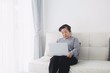 © Mallika - Elderly woman sitting on sofa and using laptop.