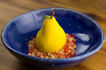 Beautiful yellow pear dessert in blue handmade dish.