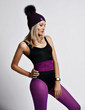 © Dmitry Lobanov - Slim blonde girl in purple sports wear, knitted hat and with smart watches is standing posing looking down on white