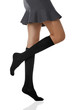 Medium bottom shot of a female figure in the gray bell-shaped skirt and black shadow-proof knee socks. The girl on tiptoe is posing on the white background. 