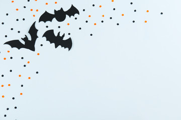 Halloween themed flat lay composition with decorative bats, on dark paper textured background with a lot of space for text. Close up, top view.