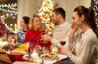 © Syda Productions - holidays, communication and celebration concept - happy young woman calling on smartphone and having christmas dinner with friends at home