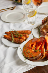 Wall Mural - grilled sliced pumpkin and whole carrot with rosemary served on white tablecloth