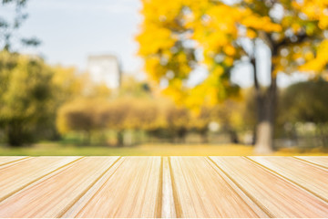 Wall Mural - Empty yellow wooden table with blurred city park on background. concept party, products, autumn background