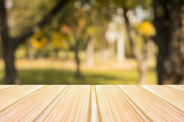 Wall Mural - Empty yellow wooden table with blurred city park on background. concept party, products, autumn background