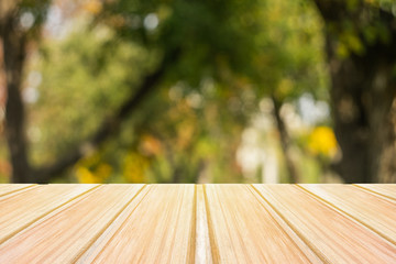Wall Mural - Empty yellow wooden table with blurred city park on background. concept party, products, autumn background