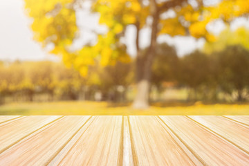 Wall Mural - Empty yellow wooden table with blurred city park on background. concept party, products, autumn background