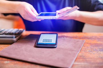 Closeup of a hand holding phone and scanning qr code. Man hand paying with qr code. Customer hand making payment through smart phone and scan code. Selective focus