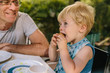 © Mareen Fischinger - Little boy having a snack outside with his father watching him