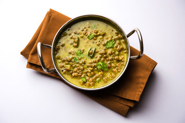 Canvas Print - Black Masoor Dal fry or Dhaba Style Sabut Red Lentil dhal tadka in green curry, served in a bowl. selective focus