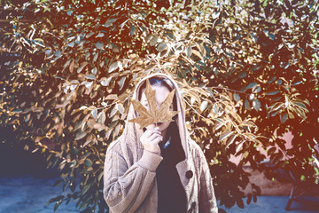 Wall Mural - Fall season concept. Beautiful middle-eastern woman holds an yellow autumn leaf