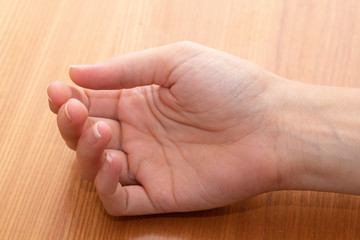 Closeup view on delicate hand of a young caucasian woman after a relaxing manicure, resting on a wooden desk with palm facing camera, details of the lines and veins close to surface of the skin.