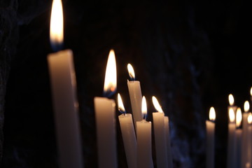 Row of lit candles on offer to the cult of the Virgin Mary (Madonna), in the cave of the sanctuary of the Mentorella, in Guadagnolo. Rome, Lazio, Italy. Sacred place of prayer, peace and silence.