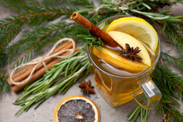 Cup fruit tea with Apple and lemon, cinnamon, star anise,  rosemary, Lollipop, fir branches on a gray background,