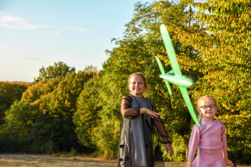 Child pilot aviator with airplane dreams of traveling in summer in nature at sunset children running happily together during beautiful sunny weather in park