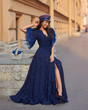 canvas print picture - Full length outdoor portrait of young beautiful elegant woman in long blue evening dress and purple hat with gray leather handbag sitting and posing at old city street on a sunny evening day