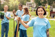 © Viktoriia - Volunteering. Young people volunteers outdoors planting trees asian girl close-up standing with shovel smiling cheerful blurred background