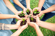 © Viktoriia - Volunteering. Young people volunteers outdoors together holding trees seedlings hands top view close-up