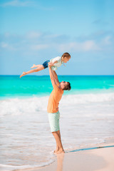 Little girl and happy dad having fun during beach vacation