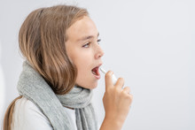 Young Girl Spraying In Her Mouth With A Spray Against The Pain In Her Throat