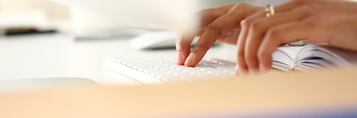 Hand of black woman type something with white wireless computer keyboard closeup