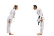 Woman with white belt in karate and a man with black belt bowing at each other
