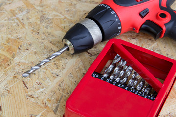 electric screwdriver with drill set,red electric drill with drill and drill set on wooden background