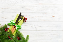 Top View Of Christmas Decorations On Wooden Background. Fork And Knife On Napkin Tied Up With Ribbon And Empty Space For Your Design. New Year Pattern Concept