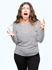 Poster - Young beautiful woman wearing stripes sweater crazy and mad shouting and yelling with aggressive expression and arms raised. Frustration concept.