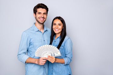 Photo of charming cute nice two people together holding their earned money wearing jeans denim smiling toothily isolated over grey color background