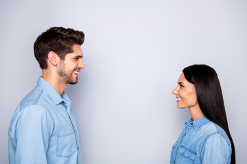 Wall Mural - Side profile photo of cheerful charming beautiful couple of two people together setting eye contact speaking with each other wearing jeans denim isolated grey color background