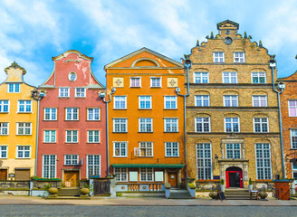 Typical colorful houses buildings with multicolored facade, outdoor porch with front steps stairs, Piwna street with cobblestone road, blue sky background, old historical city centre, Gdansk, Poland