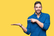 © Krakenimages.com - Young handsome man over isolated background amazed and smiling to the camera while presenting with hand and pointing with finger.