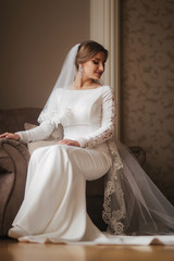 Wall Mural - Gorgeous bride sitting on the chair at the home. Beautiful woman in wedding dress