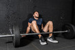 © Srdjan - Young muscular sweaty fit man with big muscles sitting on the floor with heavy barbell weight after cross training workout in the gym dark image real people