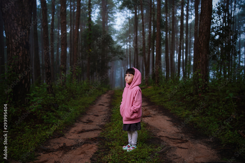 Portrait of little kid girl wearing coat jacket standing in the forest ...