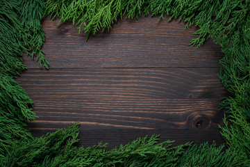 Wall Mural - Christmas green frame from fir branches on a brown board background. Frame of fir branches. Christmas card blank.