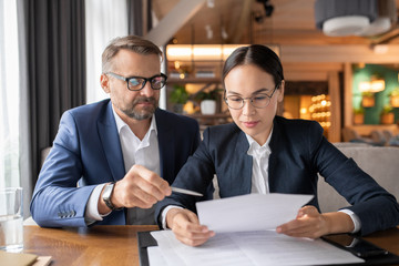 Confident businessman pointing at contract while his female colleague reading it