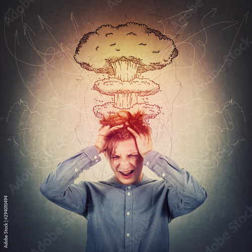 Desperate teenage boy, hands to head, messing up hair and screaming. Head explosion concept, mental health problems, anxiety and headache feeling. Losing mind function, dementia disease and migraine.