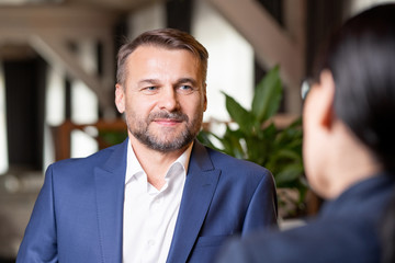 Wall Mural - Happy bearded businessman in elegant suit having discussion with colleague