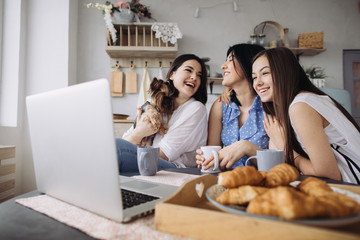 Mother and daughters talking and eating croissants in the kitchen