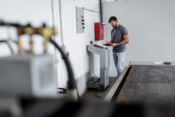 Wall Mural - Young engineer setup plasma cutter for work in metalwork workshop.